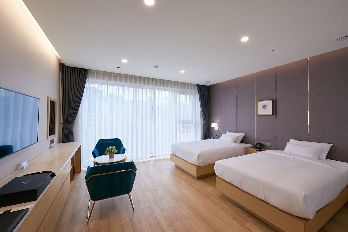 Una habitación de hotel moderna con dos camas, un escritorio, una silla y un televisor.