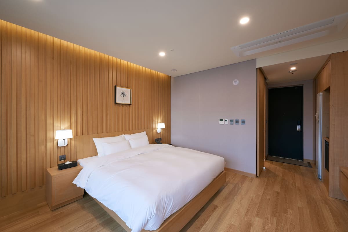 Una habitación de hotel moderna con un panel de madera, una cama grande, lámparas de noche y una mesita.