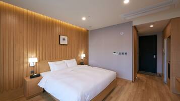 Una habitación de hotel moderna con un panel de madera, una cama grande, lámparas de noche y una mesita.