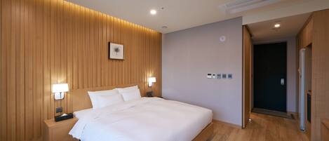 A modern hotel room with a wooden panel wall, a large bed, bedside lamps, and a nightstand.