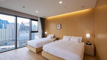 Una habitación de hotel moderna con dos camas, ventanas amplias y vistas a la ciudad.