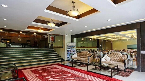 A hotel lobby with a grand staircase, seating area with sofas, and a large red carpet. - Pine Spring Hotel (Anantnag)