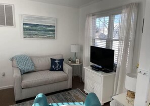 Relax in this inviting living room with a striped sofa, flat-screen TV, and a beautiful seascape artwork.