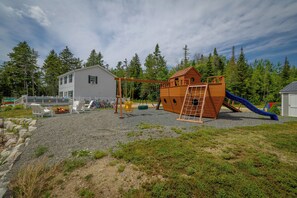 Une aire de jeux avec des balançoires, un toboggan et une structure d’escalade.