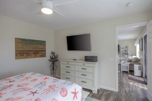 Un dormitori amb llit, un aparador, un televisor de pantalla plana i un quadre a la paret.