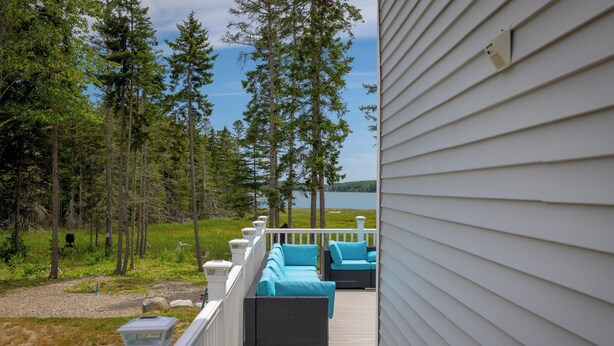Terraza con mobiliario exterior con vista a un lago y un bosque.
