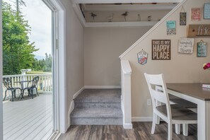 Une pièce avec un escalier en bois menant à un balcon, une chaise blanche et une table à manger.