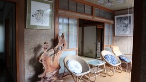 Een traditionele Japanse kamer met tatami vloerbedekking, een houten sculptuur en een schuifdeur.