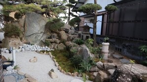 Een traditionele Japanse tuin met een vijver met koi, rotsen en diverse planten.