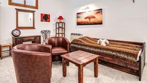A living room with a sofa, two armchairs, a wooden coffee table, a side table, a clock, a lamp, a vase, a framed picture, and a decorative item on the wall. - Cozy home in Dénia with private swimming pool, can be inside or outside (Dénia)