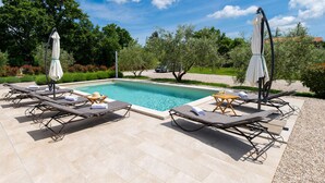Ein Poolbereich mit Liegestühlen, Sonnenschirmen und einem klaren, blauen Pool.