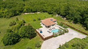 Ein Haus mit Swimmingpool, umgeben von einem gepflegten Rasen und Bäumen.