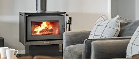 En moderne stue med en brændeovn, lædersofa og sofabord.