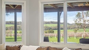 Habitación con dos ventanas grandes que dan a un viñedo.