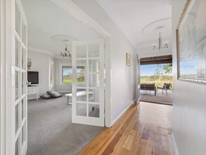 A hallway leading to a room with a television, a bench, and a view of the outdoors. - Burton Farmhouse Reconnect with Nature and Family (Wilyabrup)