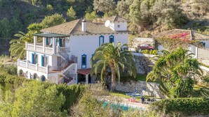 A two-story house with a balcony, a stone wall, and a swimming pool. - Cozy home in Mijas Pueblo with private swimming pool, can be inside or outside (Mijas Pueblo)