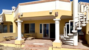 Un bâtiment jaune doté d’un patio couvert, d’un arbre à chat et d’une piscine.
