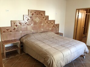 A bedroom with a bed, nightstands, and a wooden door.