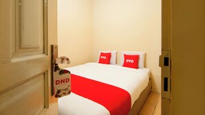 A hotel room with a bed, two pillows with 'OYO' branding, a red and white bedspread, and a door with a 'DND' sign. - OYO 2045 Hotel 211 (Parapat)