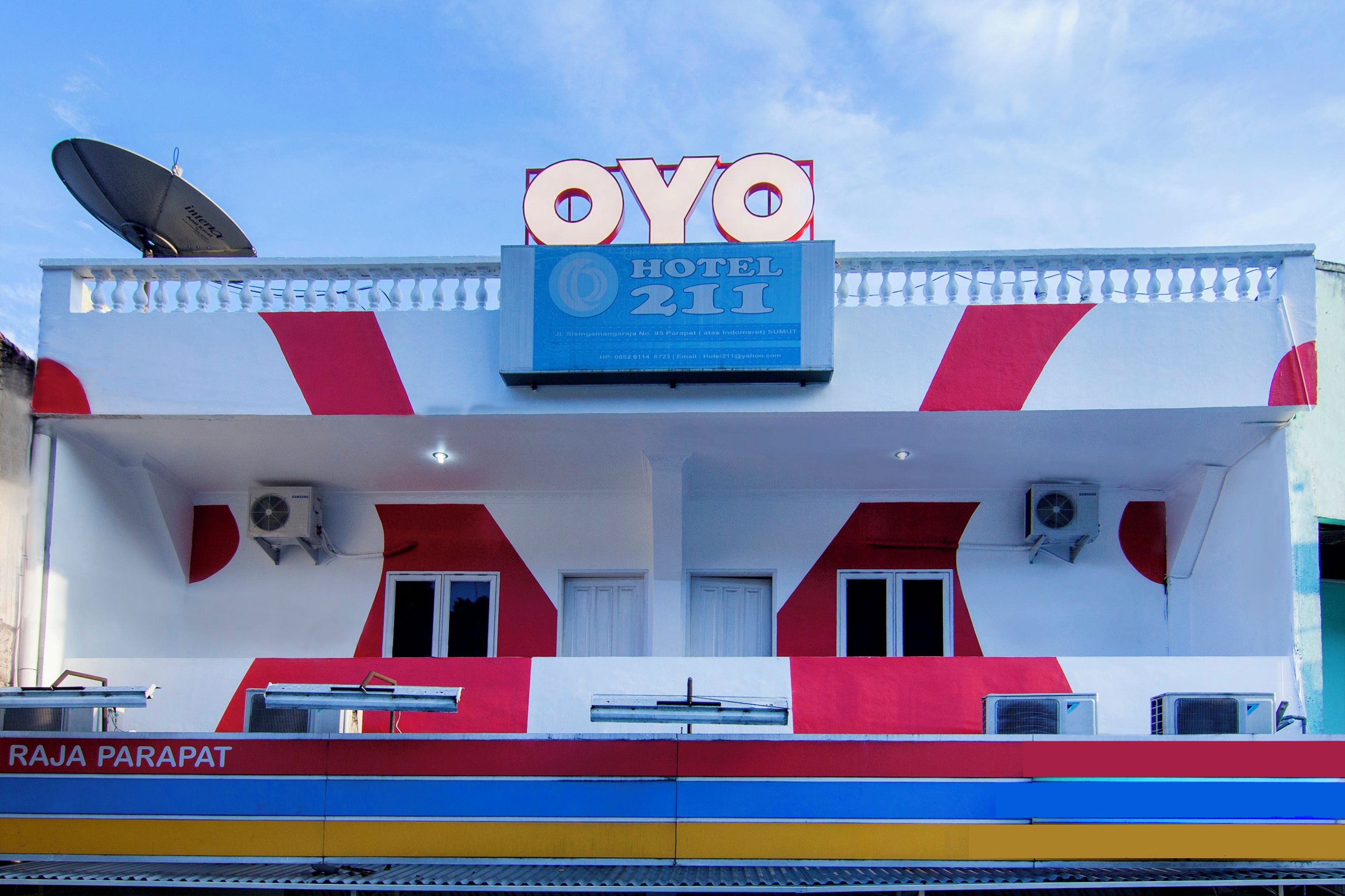 Letrero de hotel con el nombre 'OYO HOTEL 211' y una antena parabólica en el techo.