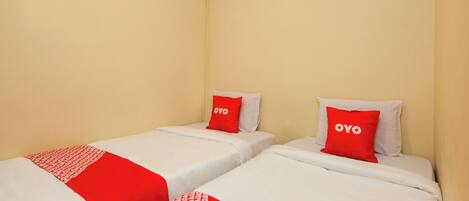 Two single beds with red and white bedding, each with a pillow labeled 'OYO'.