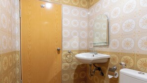 A bathroom with a wooden door, a white sink, a mirror, and patterned tiles. - OYO 2045 Hotel 211 (Parapat)