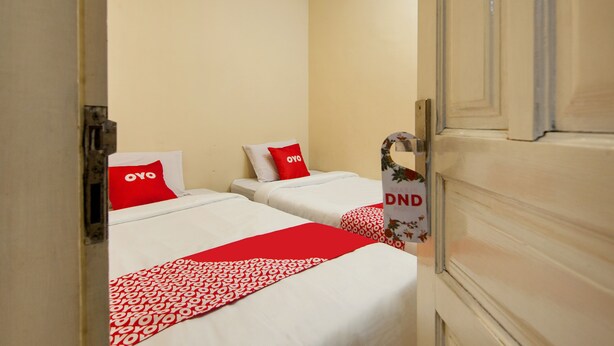 Een hotelkamer met twee bedden, elk voorzien van een rood-wit gebedekte sprei en een rood kussen met 'OVO' erop.