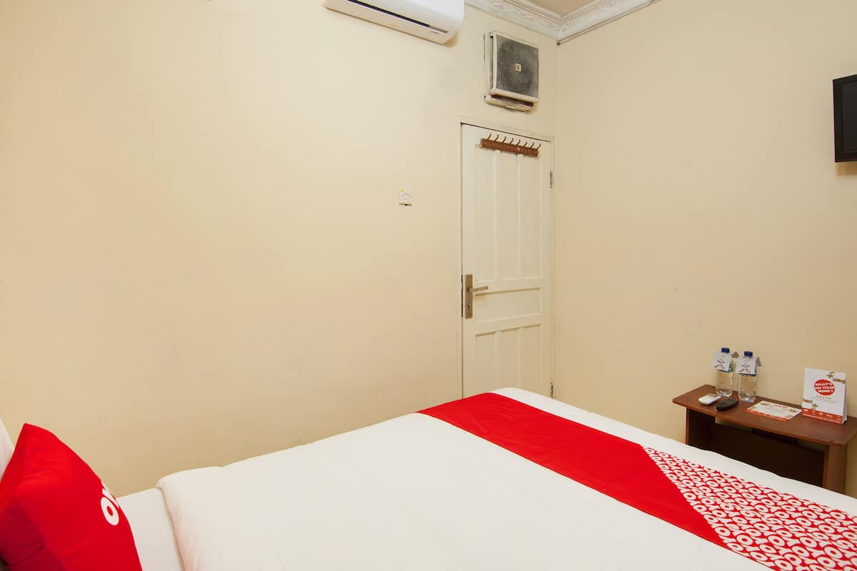 Quarto de hotel com cama, mesa de cabeceira, porta e aparelho de ar condicionado.