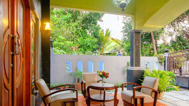 Une terrasse avec quatre chaises, une table et un vase de fleurs.