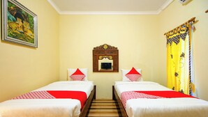 Ein Hotelzimmer mit zwei Einzelbetten, Holzboden, einem gerahmten Bild an der Wand und einem Spiegel über den Betten.