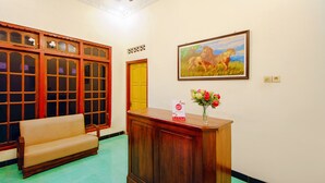 Un espace d’accueil avec un bureau en bois, un canapé et un tableau représentant un lion.