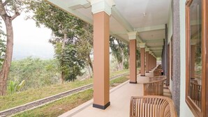 A covered outdoor area with wooden benches and a view of a railway track.