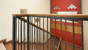 A staircase with a wooden handrail and black metal balusters, leading to a red wall with decorative elements.