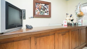A reception desk with a flat-screen TV, a telephone, and a framed picture on the wall.