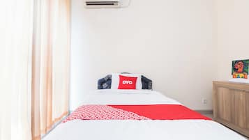 A bedroom with a bed, a pillow with the word 'YOYO', a window with curtains, and a wall-mounted air conditioner.