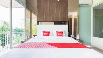 Quarto de hotel moderno com uma cama grande, varanda e vista para o verde.