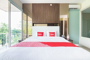 A modern hotel room with a large bed, a balcony, and a view of greenery. - OYO 2001 Taman Dayu Villa Golf View (Prigen)