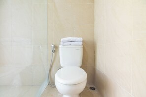 A bathroom with a toilet, a shower, and a tiled wall. - OYO 2001 Taman Dayu Villa Golf View (Prigen)