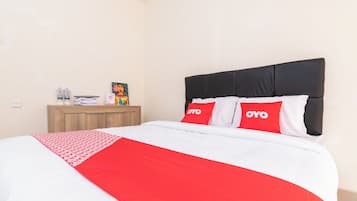 A hotel room with a bed, a nightstand, and a wall-mounted shelf.