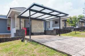 A residential building with a covered patio area, stone walls, and a small tree. - OYO 2001 Taman Dayu Villa Golf View (Prigen)