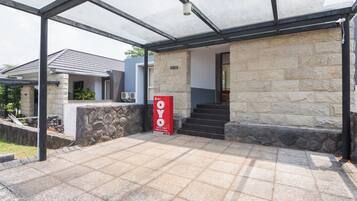 A modern villa with a stone facade, a glass entrance, and a red sign indicating a golf view.