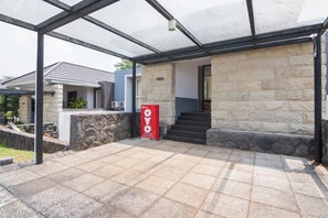 A modern villa with a stone facade, a glass entrance, and a red sign indicating a golf view. - OYO 2001 Taman Dayu Villa Golf View (Prigen)