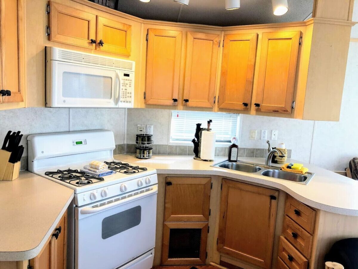 A compact kitchen with a stove, microwave, and sink.