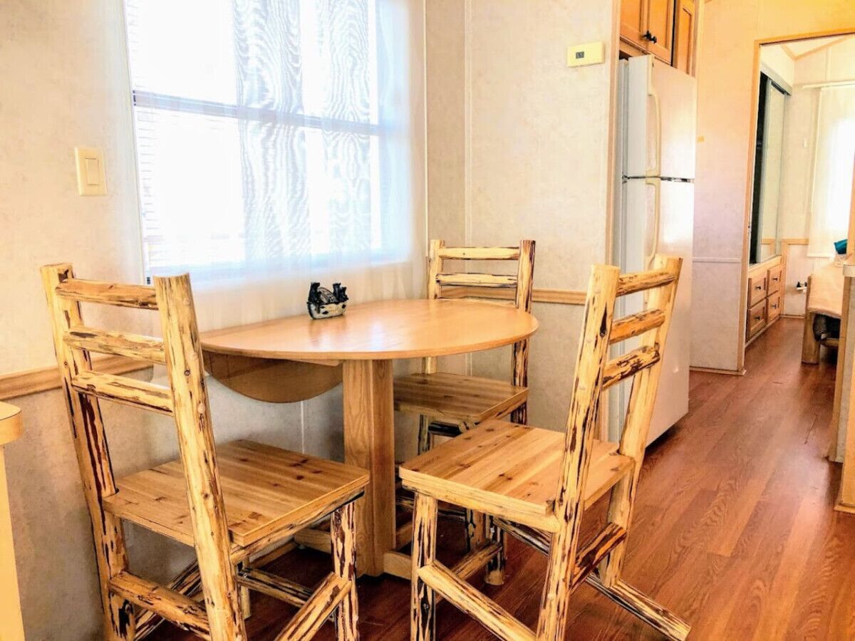 Una mesa de comedor de madera con seis sillas en una cocina con suelo y armarios de madera.