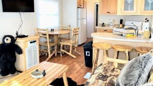A compact kitchen with wooden furniture, a built-in TV, and a small dining area.