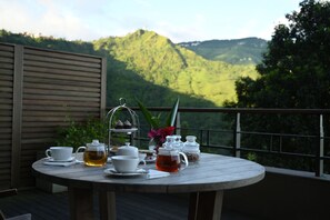 A round table with tea set and snacks on a balcony with a mountain view. - Taj Chia Kutir Resort & Spa Darjeeling (Kurseong)