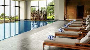 Un área de piscina interior moderna con sillones de descanso y vistas del paisaje circundante.