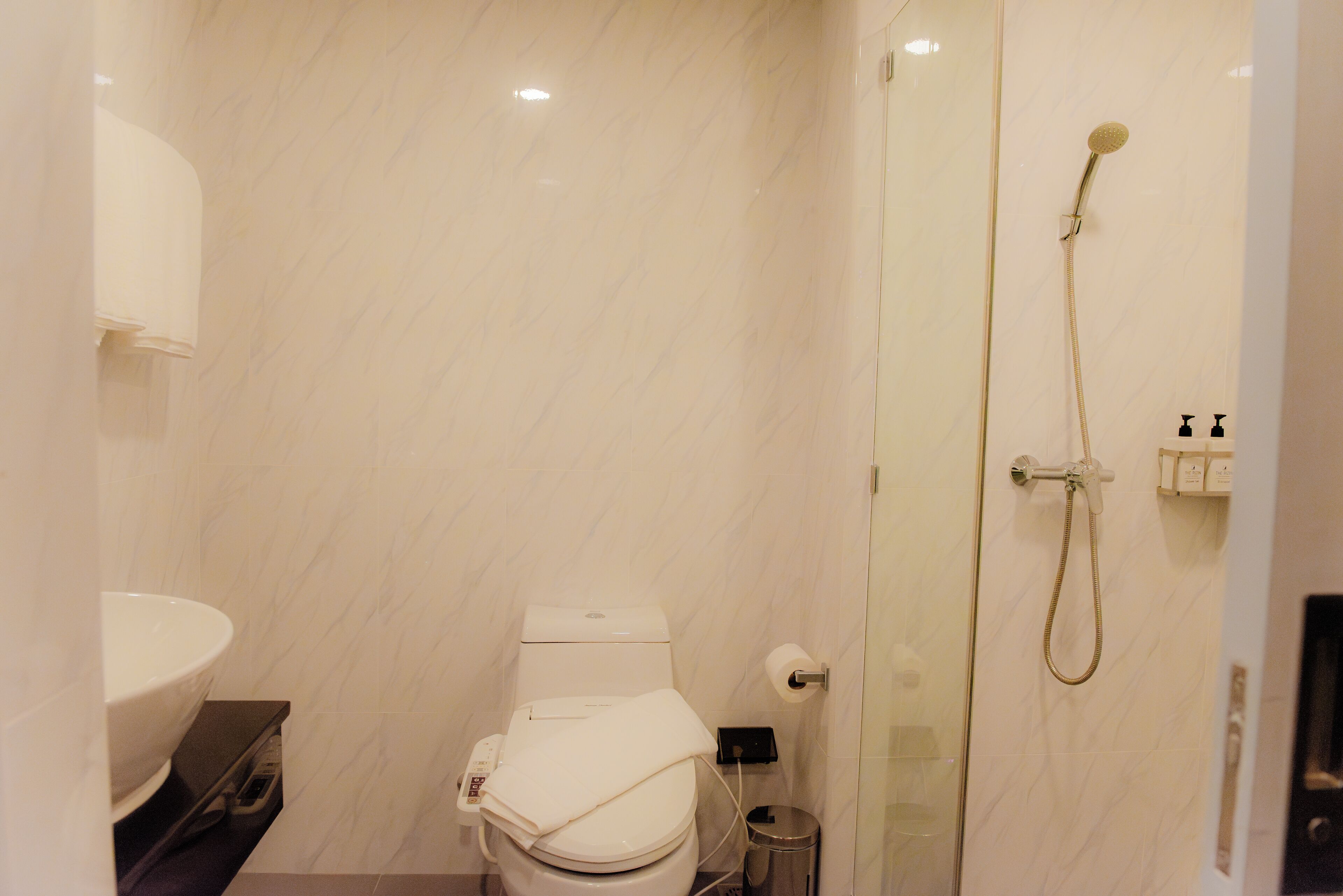 A modern bathroom with a toilet, sink, and glass-enclosed shower.