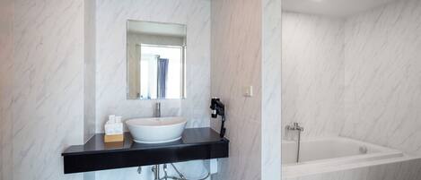 Une salle de bain moderne avec un lavabo en marbre blanc, un plan de toilette noir et une baignoire blanche.