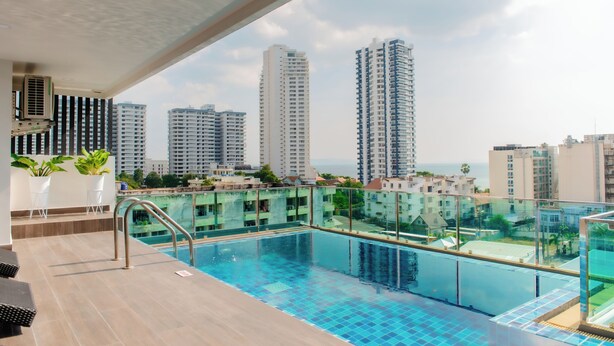 A rooftop pool with a city view, surrounded by high-rise buildings and a clear sky. - The Rizin Hotel Phratumnak (Pattaya)